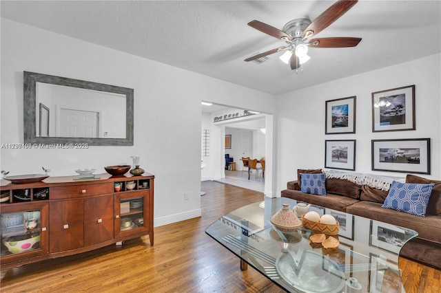 living room with ceiling fan, a textured ceiling, and light hardwood / wood-style floors