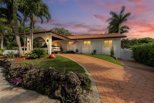 mediterranean / spanish-style home featuring a carport and a lawn