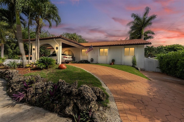 mediterranean / spanish-style home with stucco siding, fence, and a tile roof