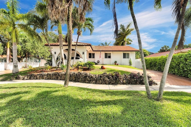 mediterranean / spanish-style house with stucco siding, a tiled roof, a front lawn, and fence