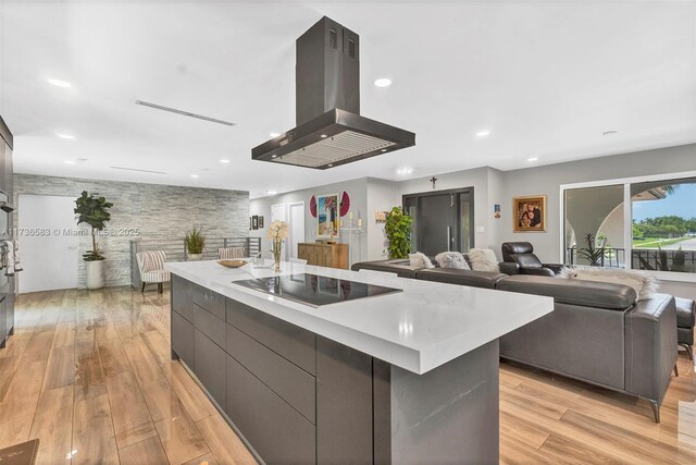 kitchen with a large island, black electric stovetop, island range hood, and light hardwood / wood-style floors