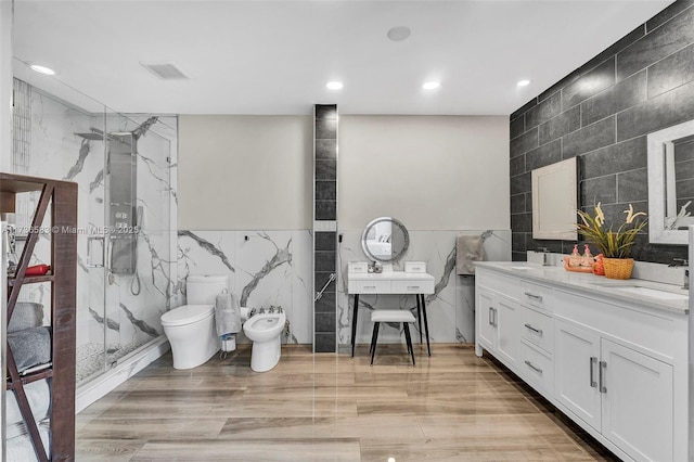 bathroom with tile walls, a bidet, a marble finish shower, and a sink