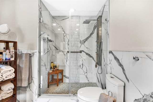 bathroom with a marble finish shower, toilet, and tile walls