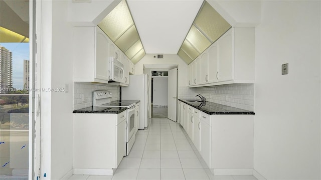 kitchen featuring lofted ceiling, sink, white appliances, dark stone counters, and white cabinets