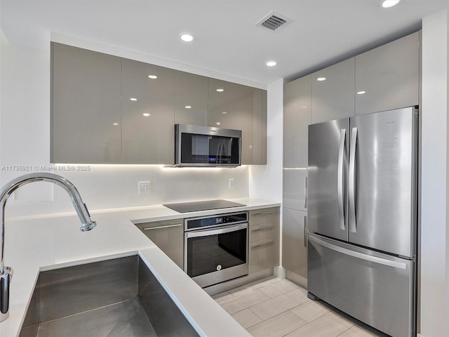 kitchen featuring stainless steel appliances, gray cabinets, and sink