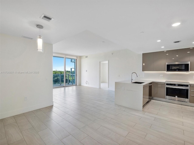 kitchen featuring sink, gray cabinets, hanging light fixtures, kitchen peninsula, and stainless steel oven