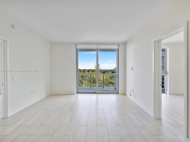 empty room with expansive windows and light hardwood / wood-style floors