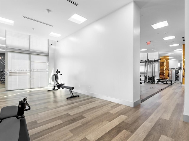 workout room featuring a towering ceiling and light hardwood / wood-style floors