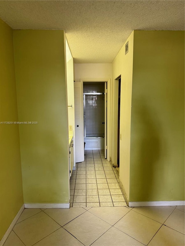 hall featuring light tile patterned floors and a textured ceiling