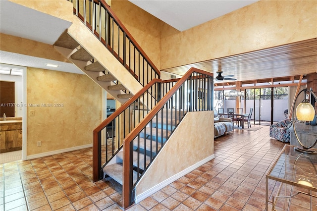 stairway with tile patterned flooring, a towering ceiling, and ceiling fan