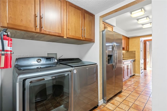 clothes washing area with cabinets, washer and clothes dryer, a textured ceiling, and light tile patterned floors