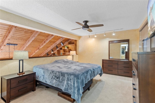 bedroom with light colored carpet, rail lighting, a textured ceiling, and vaulted ceiling with beams