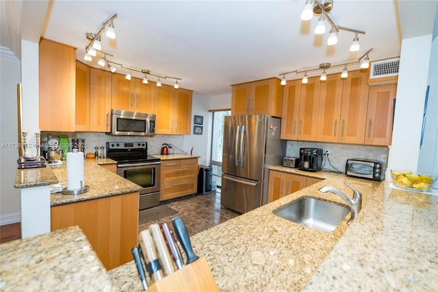 kitchen with sink, stainless steel appliances, light stone countertops, decorative backsplash, and kitchen peninsula