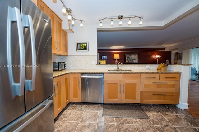 kitchen featuring sink, backsplash, kitchen peninsula, stainless steel appliances, and light stone countertops