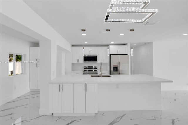 kitchen with white cabinetry, sink, decorative light fixtures, and stainless steel appliances