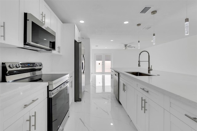 kitchen featuring pendant lighting, sink, ceiling fan, appliances with stainless steel finishes, and white cabinetry