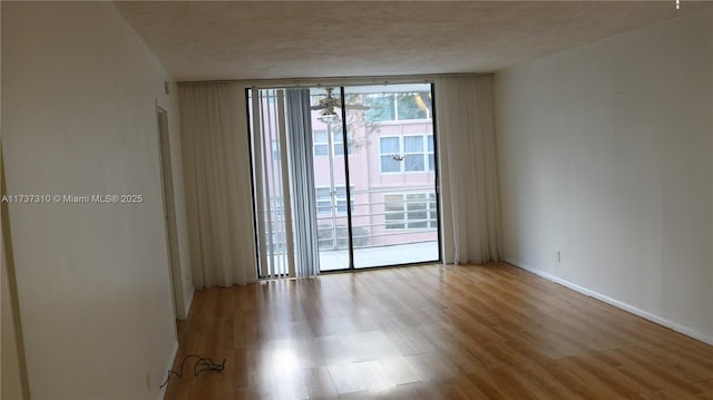 empty room featuring expansive windows, a textured ceiling, and light hardwood / wood-style floors