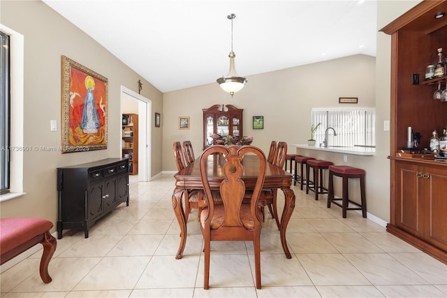 tiled dining space with lofted ceiling and sink