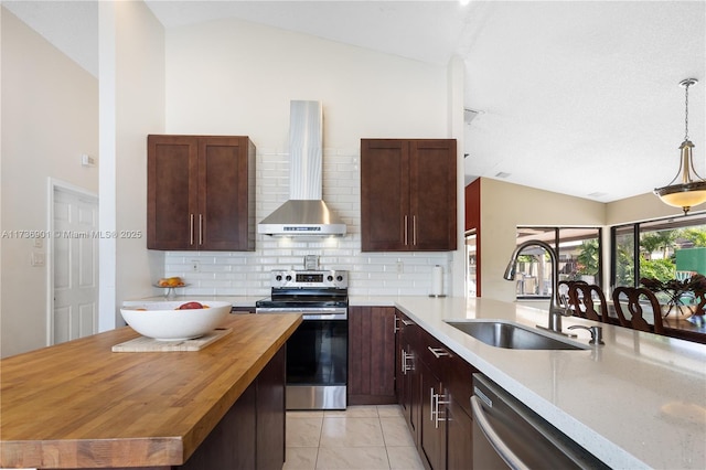 kitchen with butcher block countertops, sink, vaulted ceiling, stainless steel appliances, and wall chimney range hood