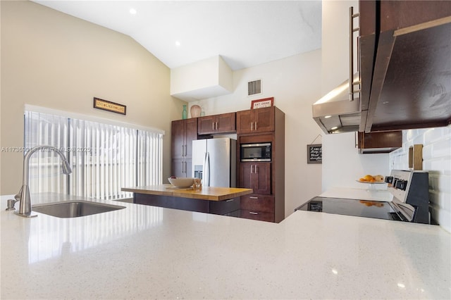 kitchen featuring vaulted ceiling, built in microwave, sink, range, and stainless steel refrigerator with ice dispenser