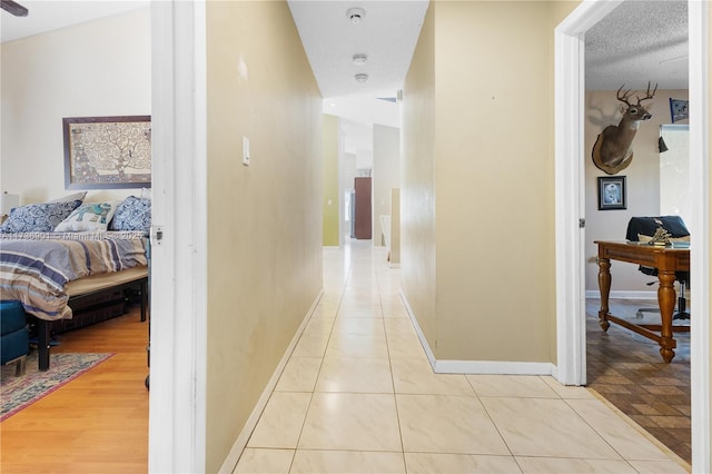 corridor with light tile patterned floors and a textured ceiling