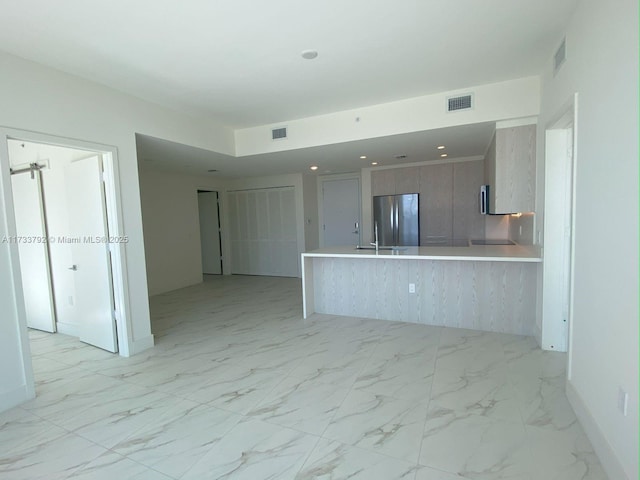 kitchen with stainless steel refrigerator, a breakfast bar, and kitchen peninsula