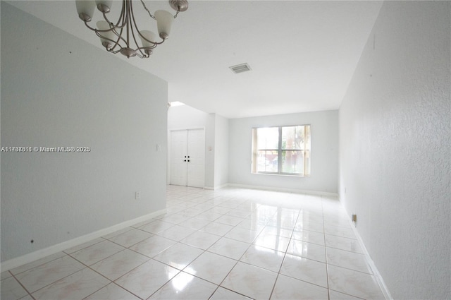 spare room featuring light tile patterned floors and an inviting chandelier