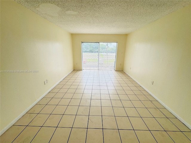 empty room with a textured ceiling and light tile patterned floors