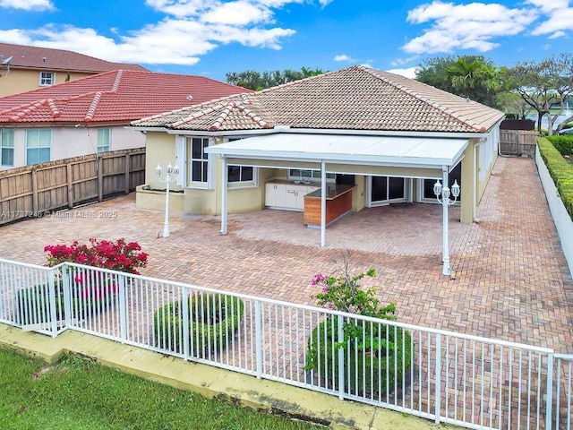 back of property with exterior kitchen and a patio area