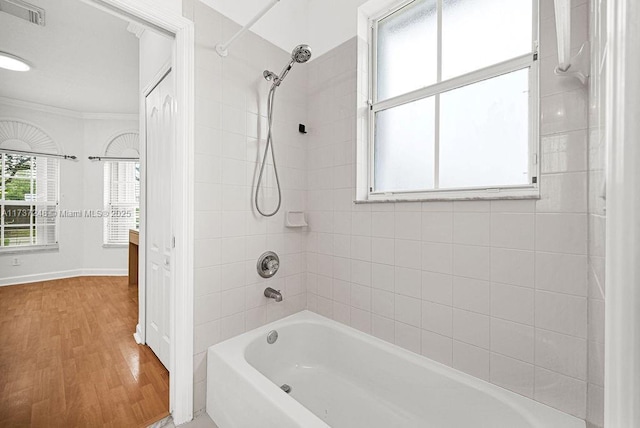 bathroom with hardwood / wood-style flooring, tiled shower / bath, and crown molding