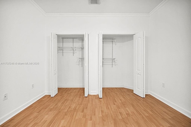 unfurnished bedroom with multiple closets, ornamental molding, and light hardwood / wood-style flooring