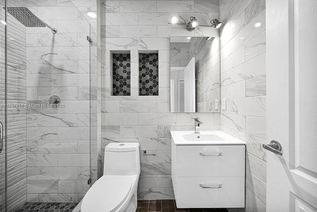 bathroom featuring vanity, a shower with door, tile walls, and toilet