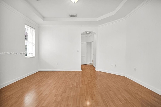 unfurnished room with crown molding, a raised ceiling, and hardwood / wood-style floors