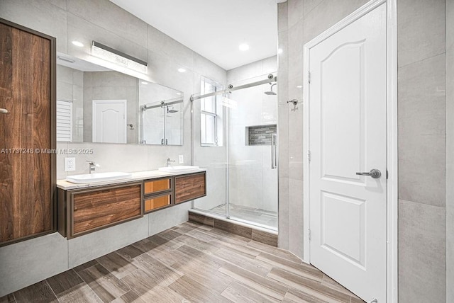 bathroom with vanity, an enclosed shower, and tile walls