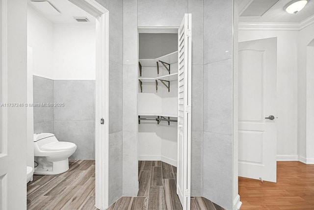 bathroom with wood-type flooring, crown molding, and toilet