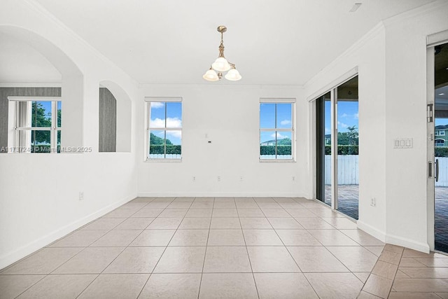 spare room with ornamental molding, light tile patterned floors, and a notable chandelier