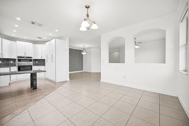 kitchen featuring crown molding, white cabinetry, backsplash, dark stone counters, and stainless steel double oven