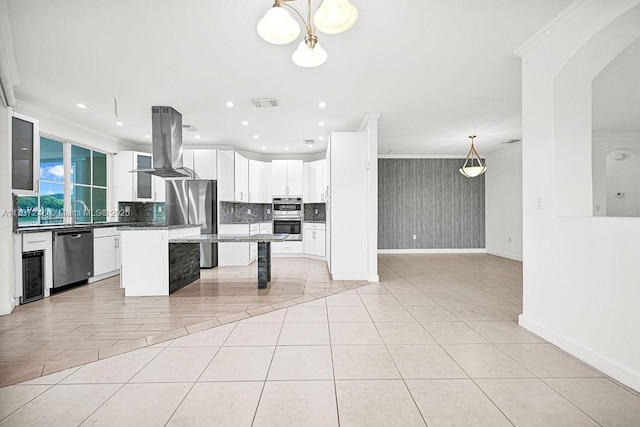 kitchen featuring appliances with stainless steel finishes, decorative light fixtures, white cabinetry, island exhaust hood, and a center island