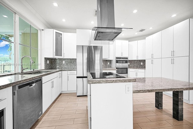 kitchen with sink, appliances with stainless steel finishes, a kitchen island, island exhaust hood, and white cabinets