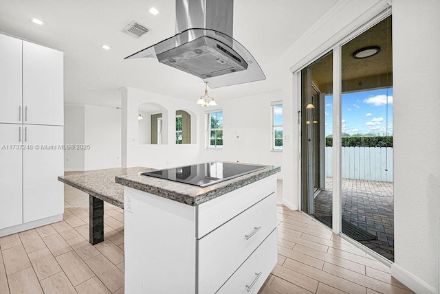 kitchen with a kitchen island, pendant lighting, island exhaust hood, black electric stovetop, and white cabinets