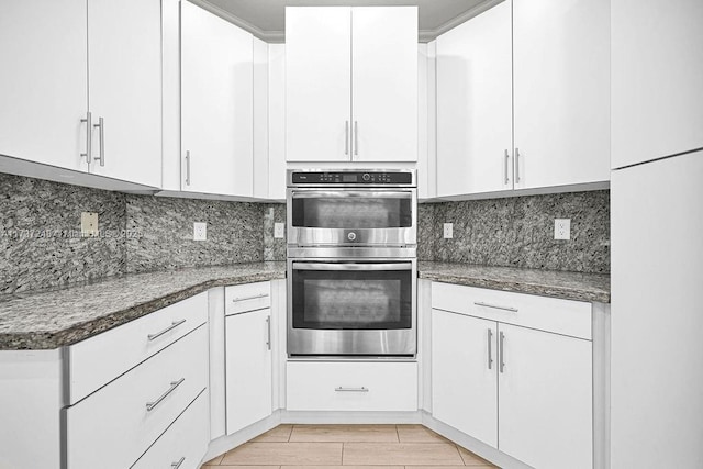 kitchen featuring tasteful backsplash, white cabinetry, and double oven