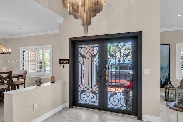 foyer with french doors, ornamental molding, and an inviting chandelier