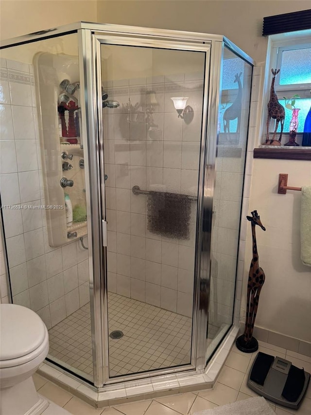 bathroom with tile patterned flooring, toilet, and a shower with shower door