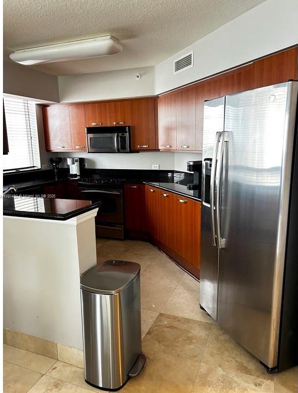 kitchen with dark countertops, visible vents, stainless steel appliances, and a textured ceiling