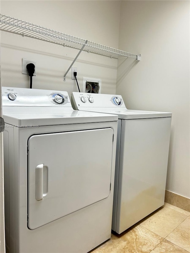 laundry room featuring washing machine and dryer, laundry area, baseboards, and light tile patterned floors