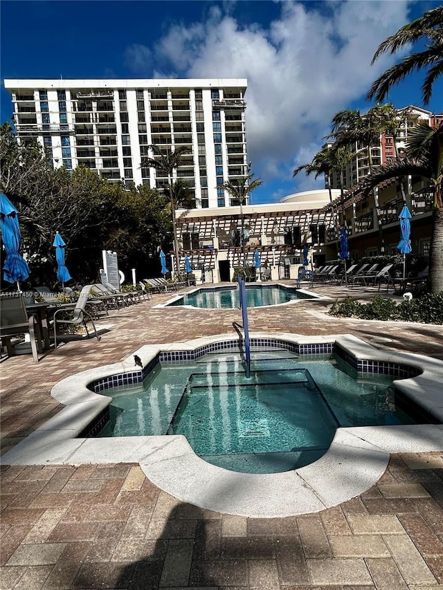 community pool with a hot tub and a patio