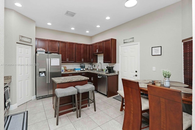 kitchen with sink, a kitchen bar, stainless steel appliances, a center island, and light tile patterned flooring