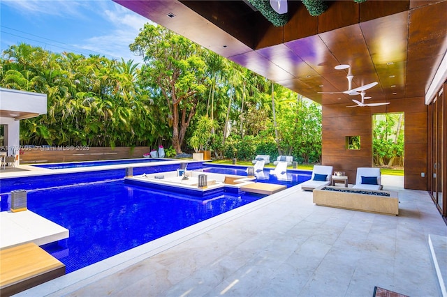 view of swimming pool featuring an in ground hot tub, ceiling fan, a patio, and a fire pit