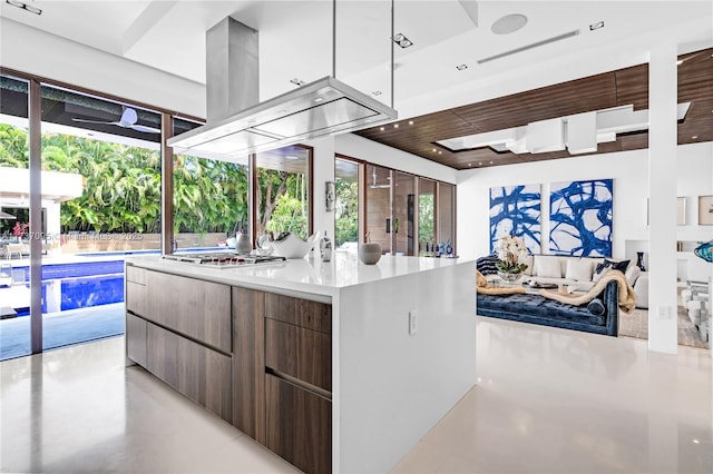 kitchen with hanging light fixtures, island exhaust hood, stainless steel gas stovetop, and a kitchen island