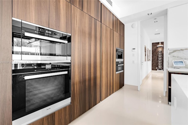 kitchen featuring built in microwave, stainless steel double oven, and tasteful backsplash